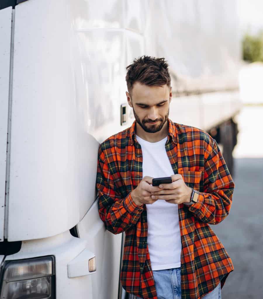 Person leaning on a truck while using his phone.
